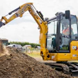 Yellow CAT 382.4 excavator dumping soil at a construction site with operator visible in cab