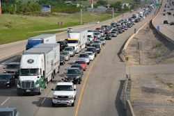 Heavy traffic congestion on multi-lane highway with semi-trucks and passenger vehicles during peak hours
