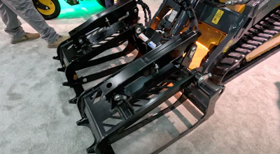 Black skid steer loader with attachment displayed at equipment trade show
