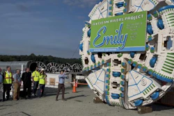 Tunnel boring machine with Emily Clean Rivers Project branding at construction site with workers