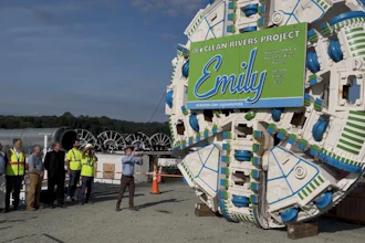 Tunnel boring machine with Emily Clean Rivers Project branding at construction site with workers