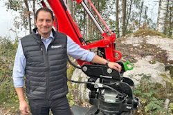 Man in Weidemann vest posing with red X07 wheel loader in forest setting