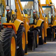 Row of yellow and black heavy construction wheel loaders parked in line at an equipment yard