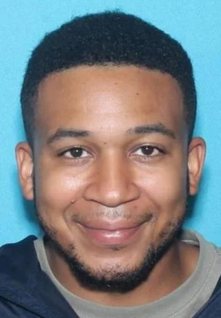 mugshot of Marvin Grant a man with short dark hair and facial hair wearing a dark shirt against a blue background