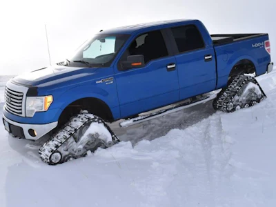 Blue Ford F-150 pickup truck with snow tracks on snowy terrain