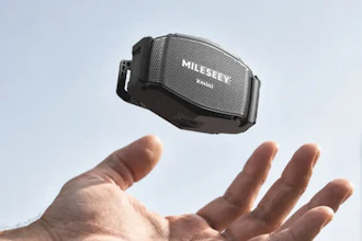 Hand holding Mileev portable Bluetooth speaker against sky background