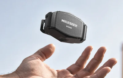 Hand holding Mileev portable Bluetooth speaker against sky background