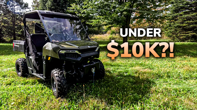 Olive green Polaris Ranger UTV parked on grass with pricing text 'Under $10K?!' overlaid, surrounded by trees