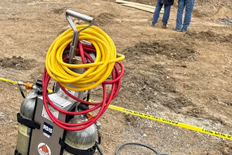 Franklin County, Pennsylvania site of fatal trench collapse with yellow excavator, workers in safety gear, and equipment including hoses on dirt ground