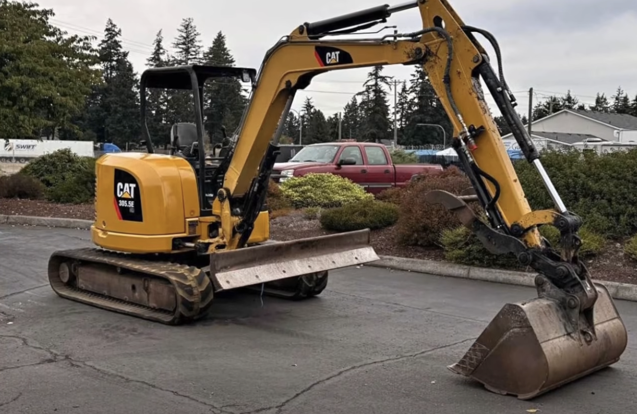 Yellow Caterpillar mini excavator with bucket attachment parked on asphalt in outdoor lot