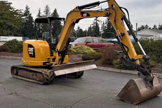 Yellow Caterpillar mini excavator with bucket attachment parked on asphalt in outdoor lot