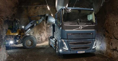 Volvo truck and forklift operating in underground mine tunnel with LED lighting