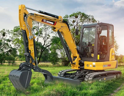Yellow XCMG mini excavator with bucket attachment on grass field with trees