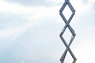 Yellow XCMG XG2632AC scissor lift platform fully extended against city skyline backdrop